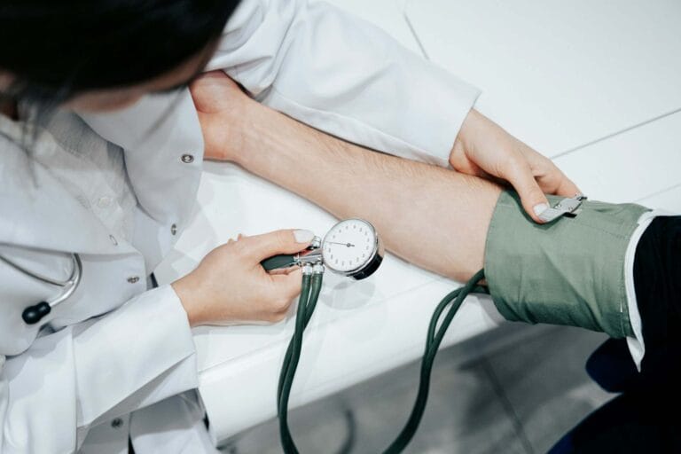 A healthcare professional measures a patient's blood pressure using a sphygmomanometer on a clinical white surface, Cambodia Healthcare Market Expansion.